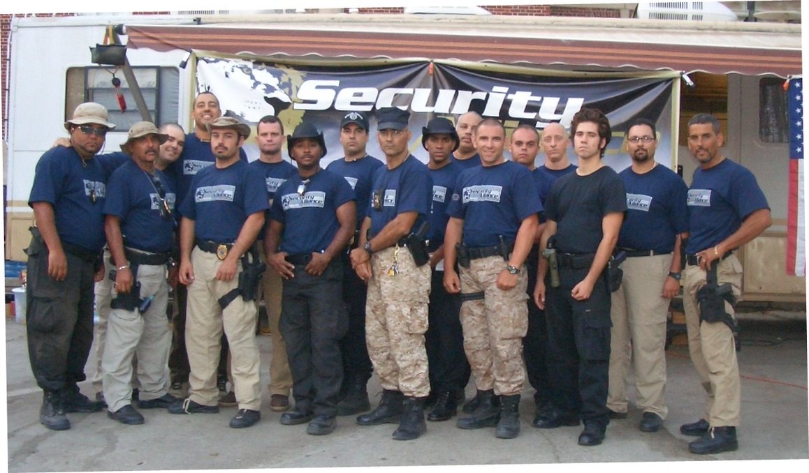 Security Alliance personnel assembled under a canopy at a staging area